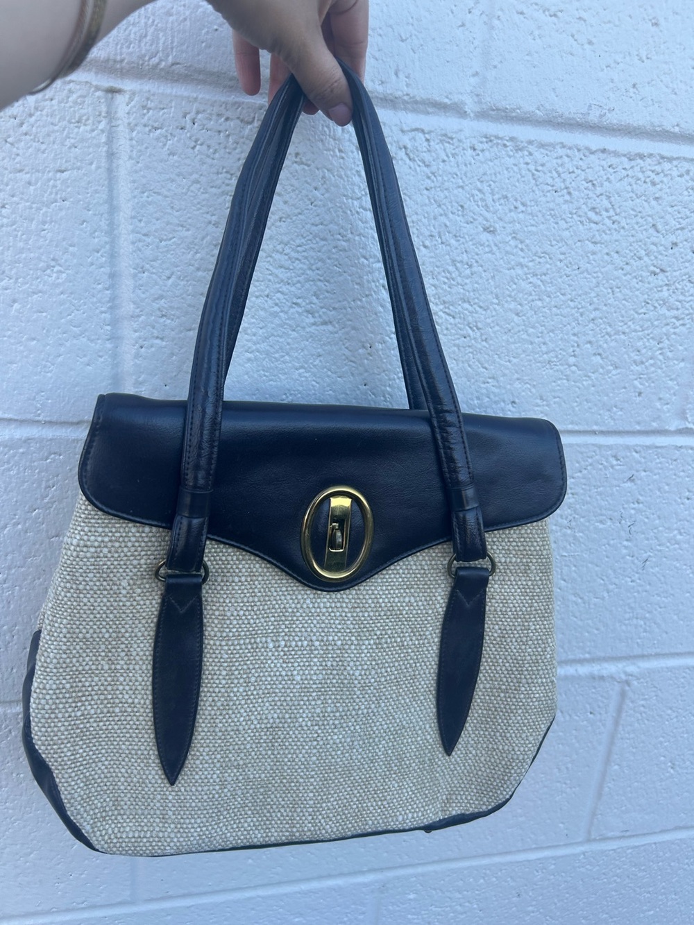 appears to be a vintage Etienne Aigner straw and navy leather shoulder bag